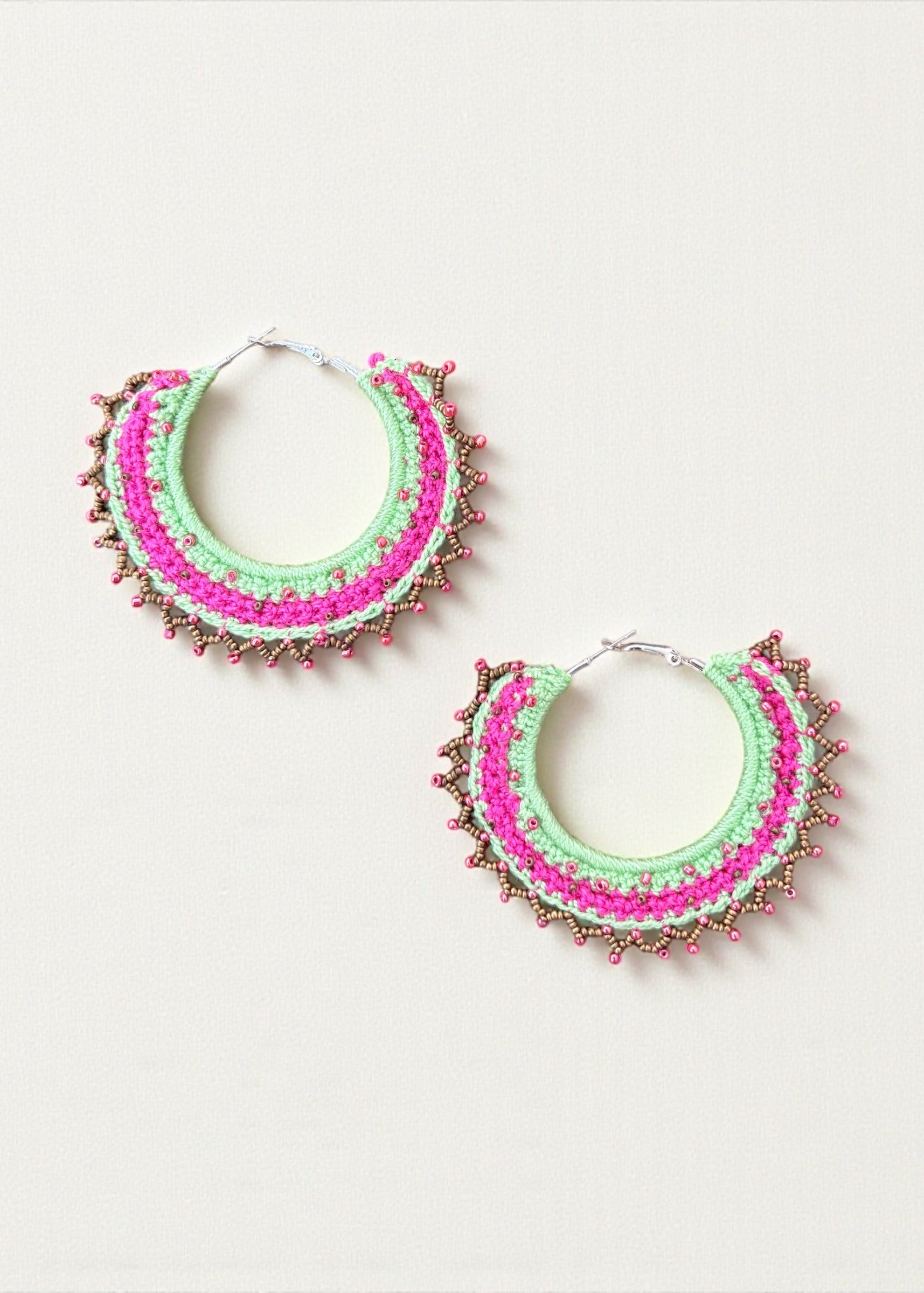 Neon green and hot pink crochet hoop earrings with gold and pink beads by ThatRomeo on a light background.
