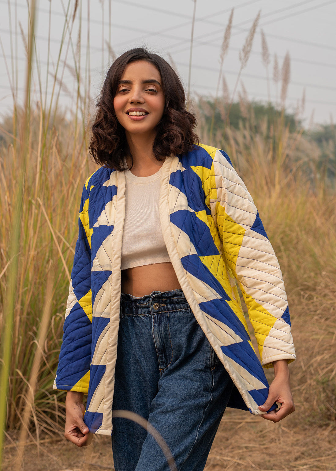 Model wearing ThatRomeo’s Sky Circuit Quilted Jacket — cotton patchwork jacket in cobalt blue, yellow, and cream tones with open front.
