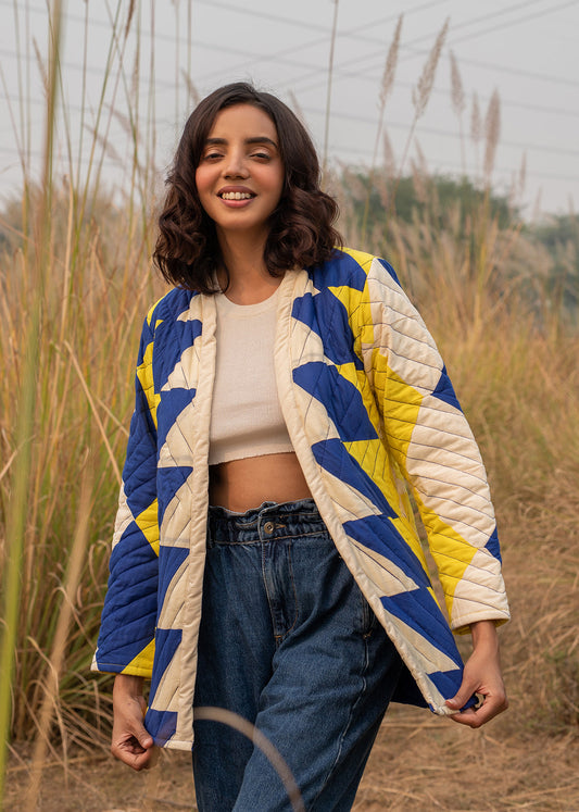 Model wearing ThatRomeo’s Sky Circuit Quilted Jacket — cotton patchwork jacket in cobalt blue, yellow, and cream tones with open front.