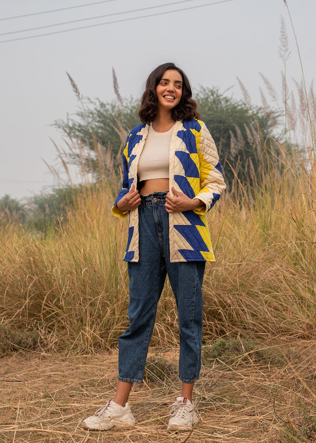 Model wearing ThatRomeo’s Sky Circuit Quilted Jacket — cotton patchwork jacket in cobalt blue, yellow, and cream tones with open front.