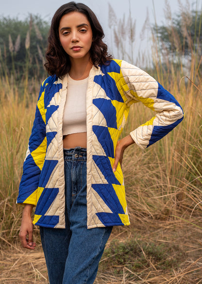 Model wearing ThatRomeo’s Sky Circuit Quilted Jacket — cotton patchwork jacket in cobalt blue, yellow, and cream tones with open front.