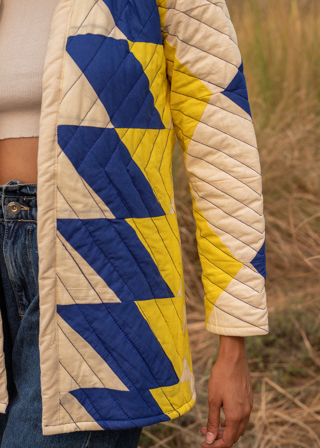 Model wearing ThatRomeo’s Sky Circuit Quilted Jacket — cotton patchwork jacket in cobalt blue, yellow, and cream tones with open front.