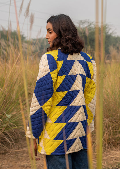 Model wearing ThatRomeo’s Sky Circuit Quilted Jacket — cotton patchwork jacket in cobalt blue, yellow, and cream tones with open front.