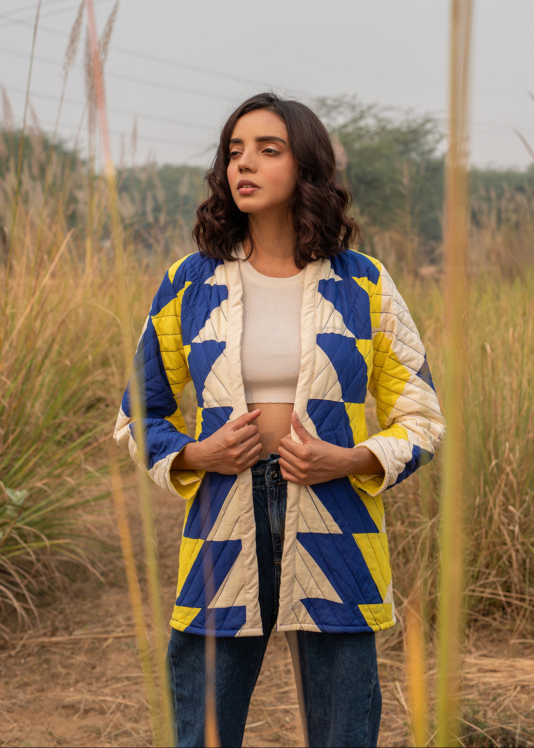 Model wearing ThatRomeo’s Sky Circuit Quilted Jacket — cotton patchwork jacket in cobalt blue, yellow, and cream tones with open front.